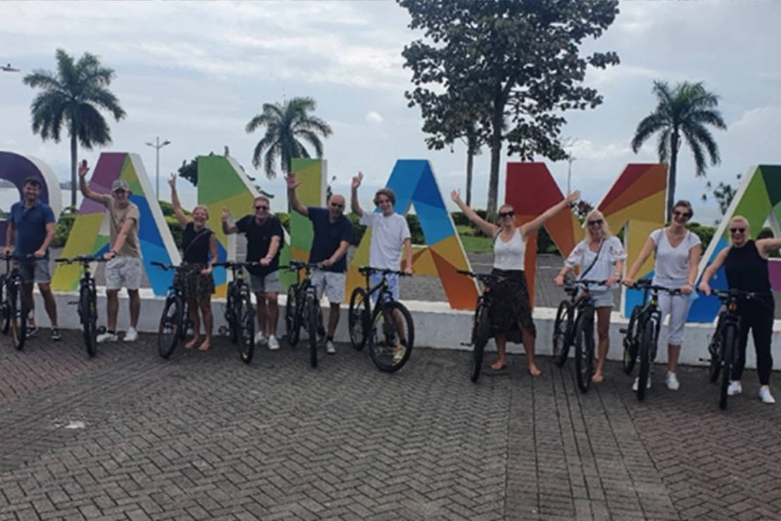 tour panamá en grupo tour en bicicleta frente al logo de panamá